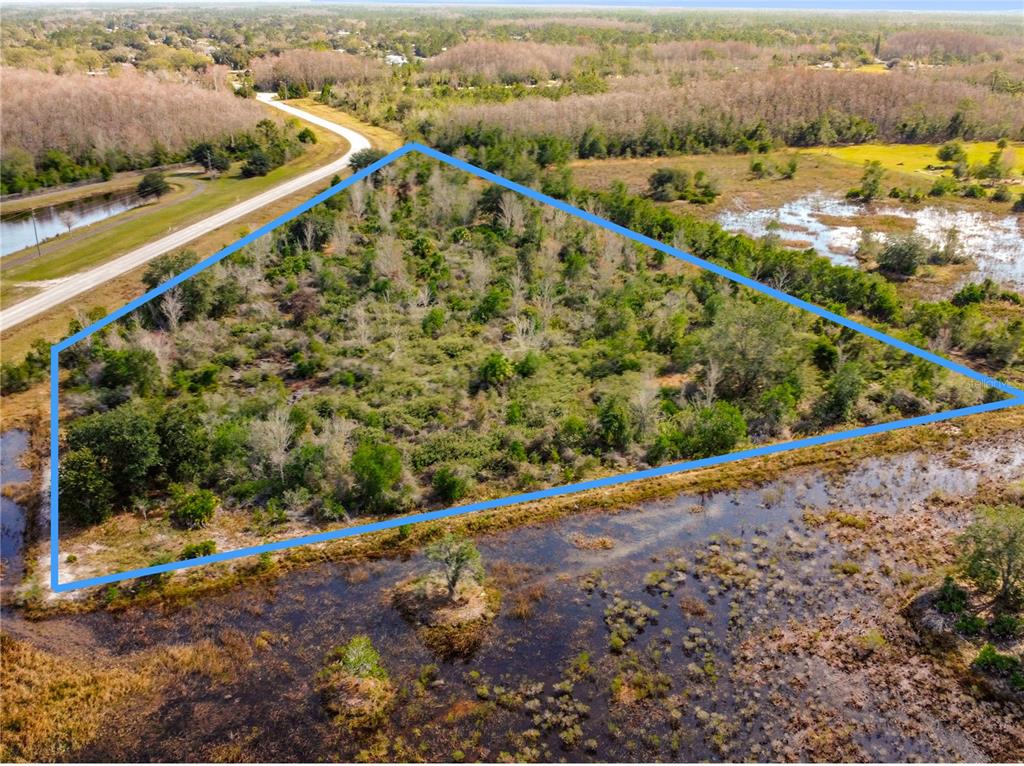 An aerial view shows a triangular, wooded plot of land bordered by water and roads — 0 COMMUNITY CENTER ROAD, ST CLOUD, FL