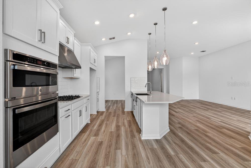A modern kitchen features white cabinetry, stainless steel appliances, and a quartz-topped island — 12743 DOCKYARD TRAIL, PALMETTO, FL