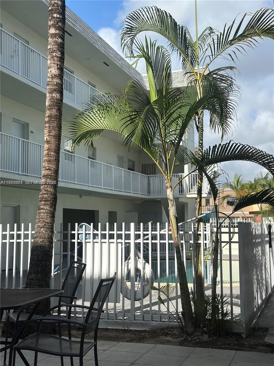 A view of a multi-story apartment building exterior with a palm tree and swimming pool — 12890 NE 8th Ave # 101, North Miami FL 33161, NORTH MIAMI, FL