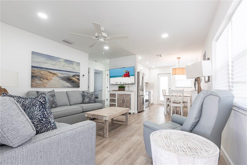 A bright living room features a grey sofa, a recliner, and an open-concept kitchen area — 6020 MIDNIGHT PASS ROAD UNIT 7, SARASOTA, FL
