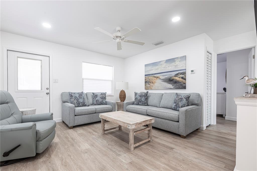 A living room with light wood flooring, gray sofas, a recliner, and a coffee table — 6020 MIDNIGHT PASS ROAD UNIT 7, SARASOTA, FL