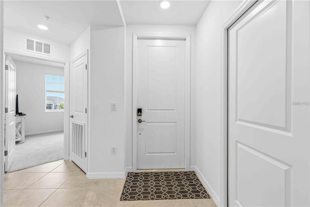 A bright entryway features a white front door, tiled flooring, and an adjacent bedroom doorway — 12240 WELLEN GOLF STREET UNIT 208, VENICE, FL
