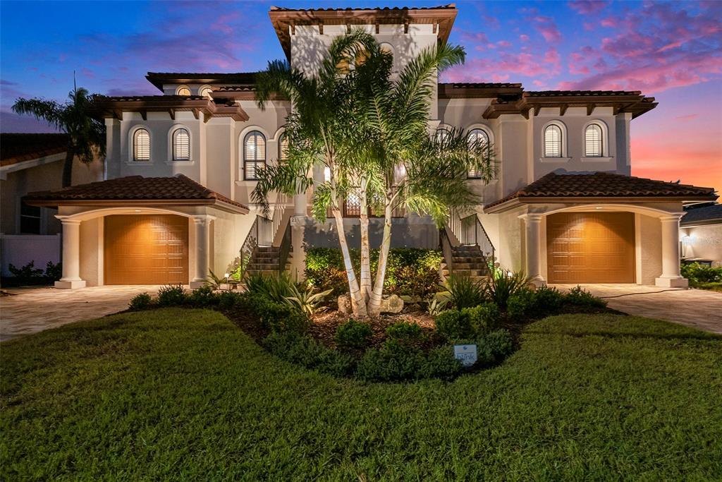 A two-story Mediterranean-style house with two garages, arched windows, and a central palm tree — 231 MIDWAY ISLAND, CLEARWATER BEACH, FL