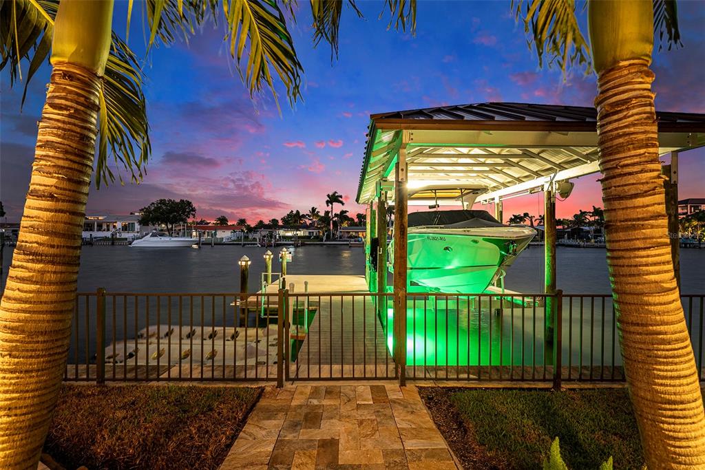 A boat is docked under a covered lift at a waterfront property at sunset — 231 MIDWAY ISLAND, CLEARWATER BEACH, FL
