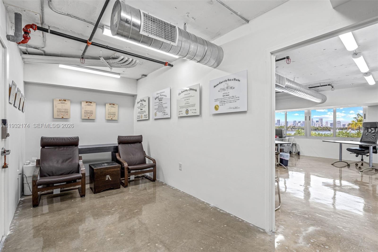 An office waiting area with two leather chairs, framed certificates, and an adjacent workspace — 1200 West Ave # 7, Miami Beach FL 33139, MIAMI BEACH, FL
