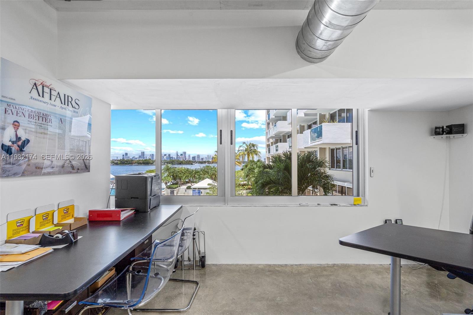 An office room features a long desk, clear chairs, concrete floors, and a waterfront view — 1200 West Ave # 7, Miami Beach FL 33139, MIAMI BEACH, FL