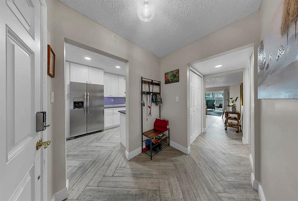 An entryway with wood-look tile flooring leads to a kitchen and a hallway — 8799 BARDMOOR BOULEVARD UNIT 205, SEMINOLE, FL