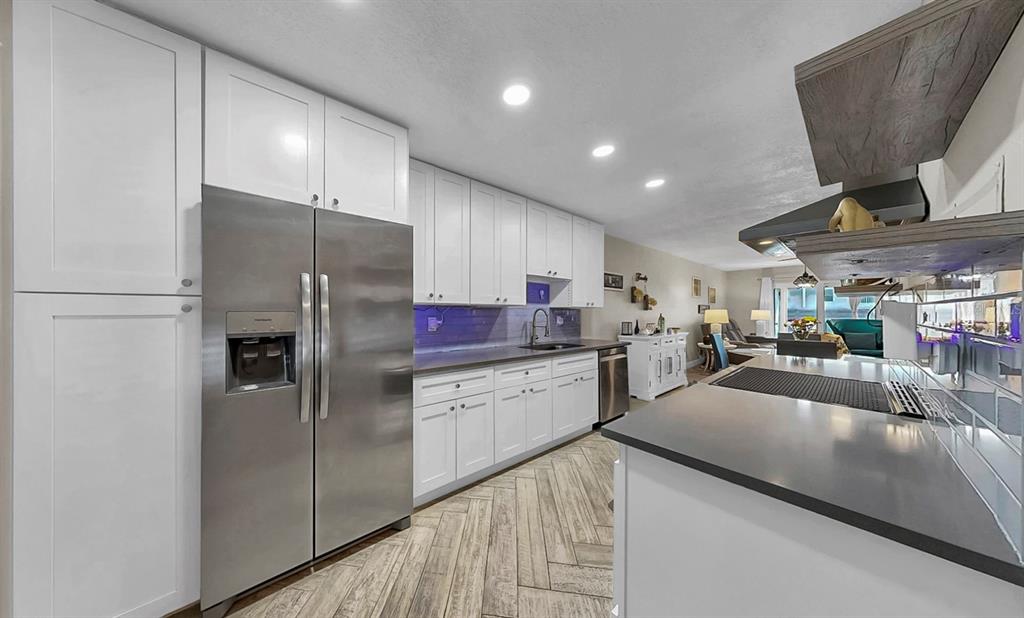 A modern kitchen features white cabinets, stainless steel appliances, and a herringbone-patterned tile floor — 8799 BARDMOOR BOULEVARD UNIT 205, SEMINOLE, FL