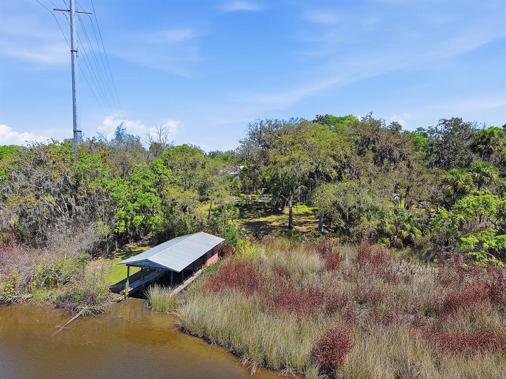 An aerial view shows a boat dock on a riverbank surrounded by trees and marshland — 6491 SPRUCE CREEK ROAD, PORT ORANGE, FL