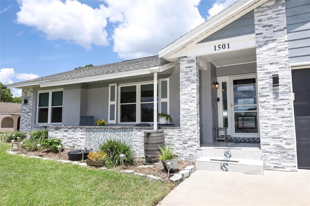 The exterior of a single-story house features gray stucco walls, stone veneer accents, and a porch — 1501 ELF STONE COURT, CASSELBERRY, FL