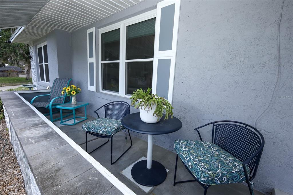 A covered porch features a gray exterior wall, a window with shutters, and patio furniture — 1501 ELF STONE COURT, CASSELBERRY, FL