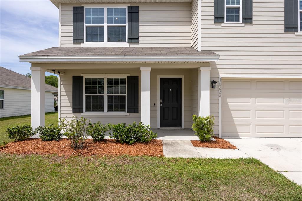 The exterior of a two-story house features beige siding, a front porch, and a garage — 16372 NW 190TH STREET, HIGH SPRINGS, FL