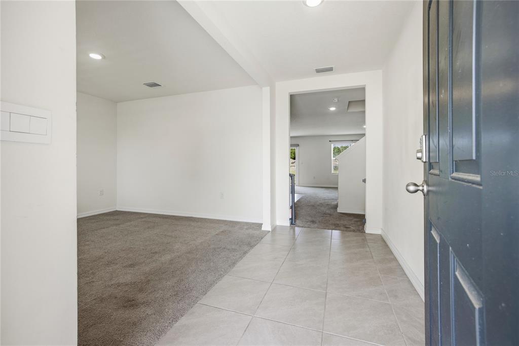 An entryway with tiled flooring leads to a carpeted room and an adjacent living area — 16372 NW 190TH STREET, HIGH SPRINGS, FL