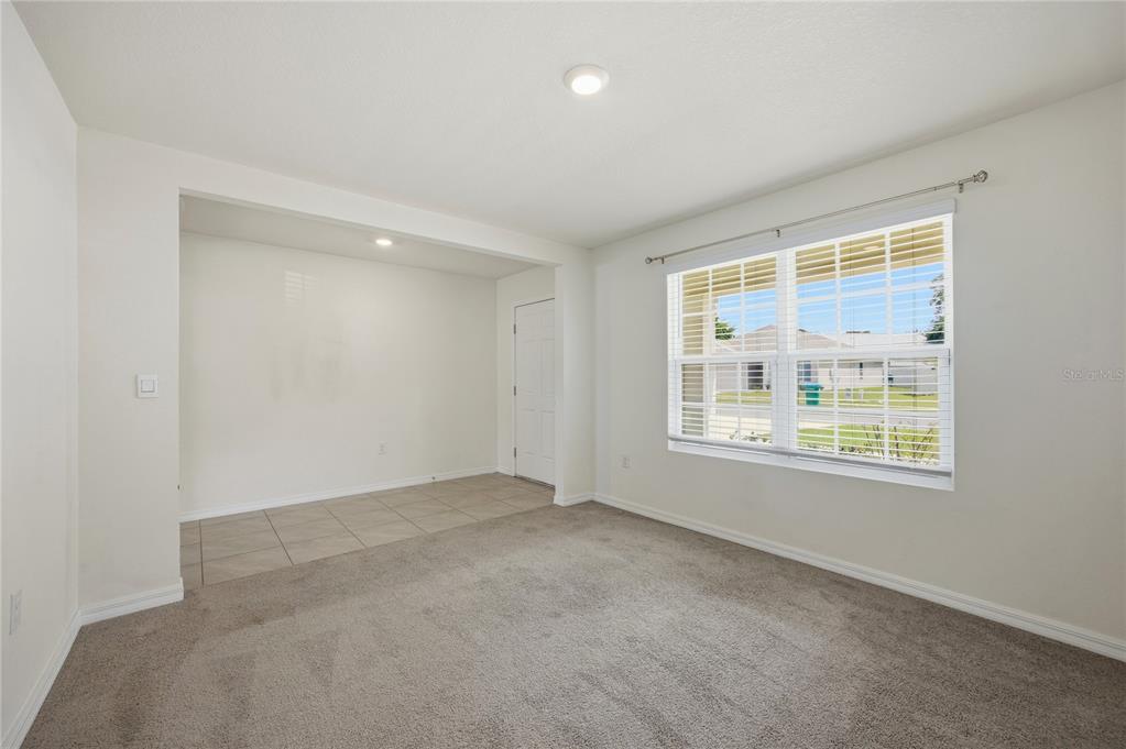 A room with carpeted flooring, a tiled alcove, and a large window with blinds — 16372 NW 190TH STREET, HIGH SPRINGS, FL