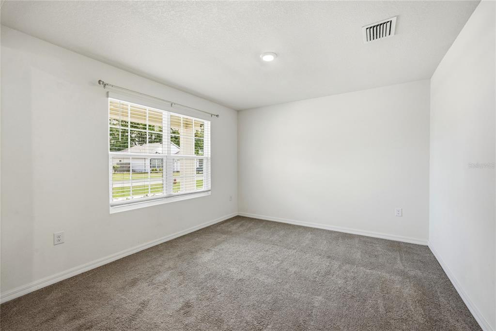 An empty bedroom features white walls, gray carpeting, a single window, and a ceiling light — 16372 NW 190TH STREET, HIGH SPRINGS, FL