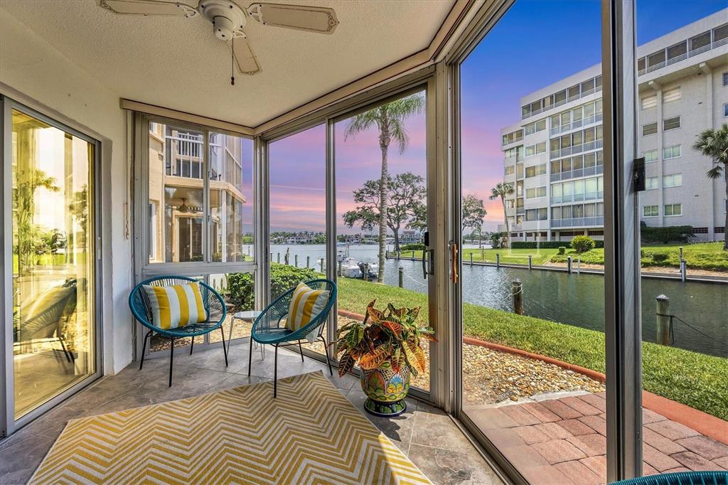 A multi-story apartment building with screened balconies overlooks a canal and a grassy lawn — 1350 N PORTOFINO DRIVE UNIT 107, SARASOTA, FL