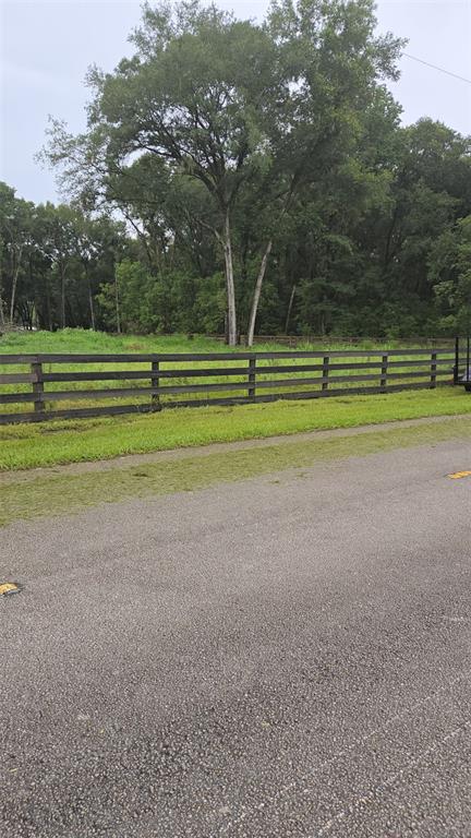 A wooden fence borders a grassy field with large trees under an overcast sky — 890 GRAND RONDO W, CRESCENT CITY, FL