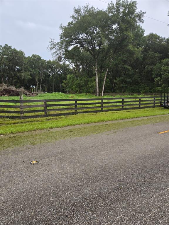 A wooden fence borders a grassy lot with mature trees under a cloudy sky — 890 GRAND RONDO W, CRESCENT CITY, FL