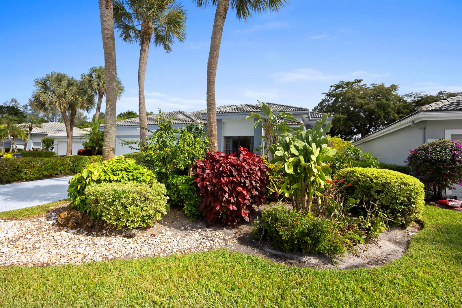 A landscaped front yard features a variety of tropical plants, cacti, and palm trees — 10106 Spyglass Way, Boca Raton FL 33498, BOCA RATON, FL