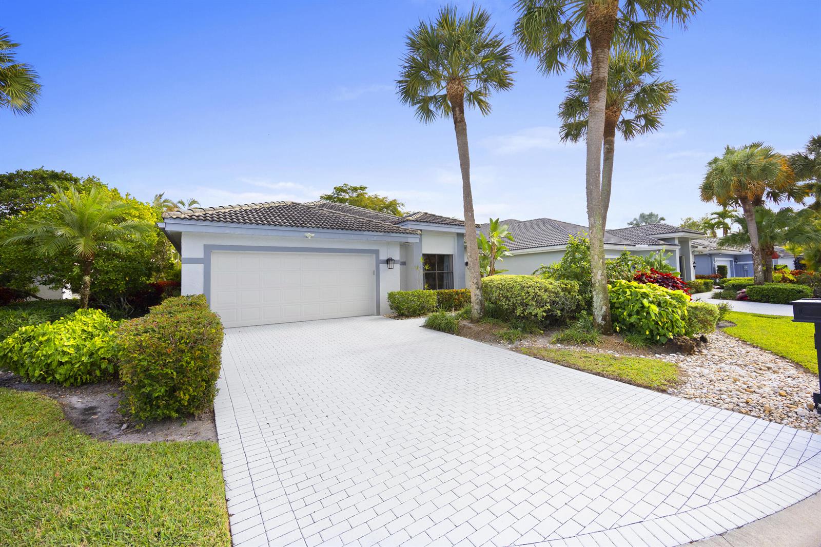 A single-story house with a white garage door and a paved driveway under palm trees — 10106 Spyglass Way, Boca Raton FL 33498, BOCA RATON, FL