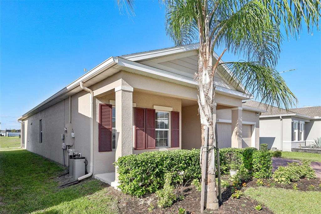 A tan single-story house features a front porch, red shutters, and a palm tree — 5585 VIGO LOOP, ST CLOUD, FL