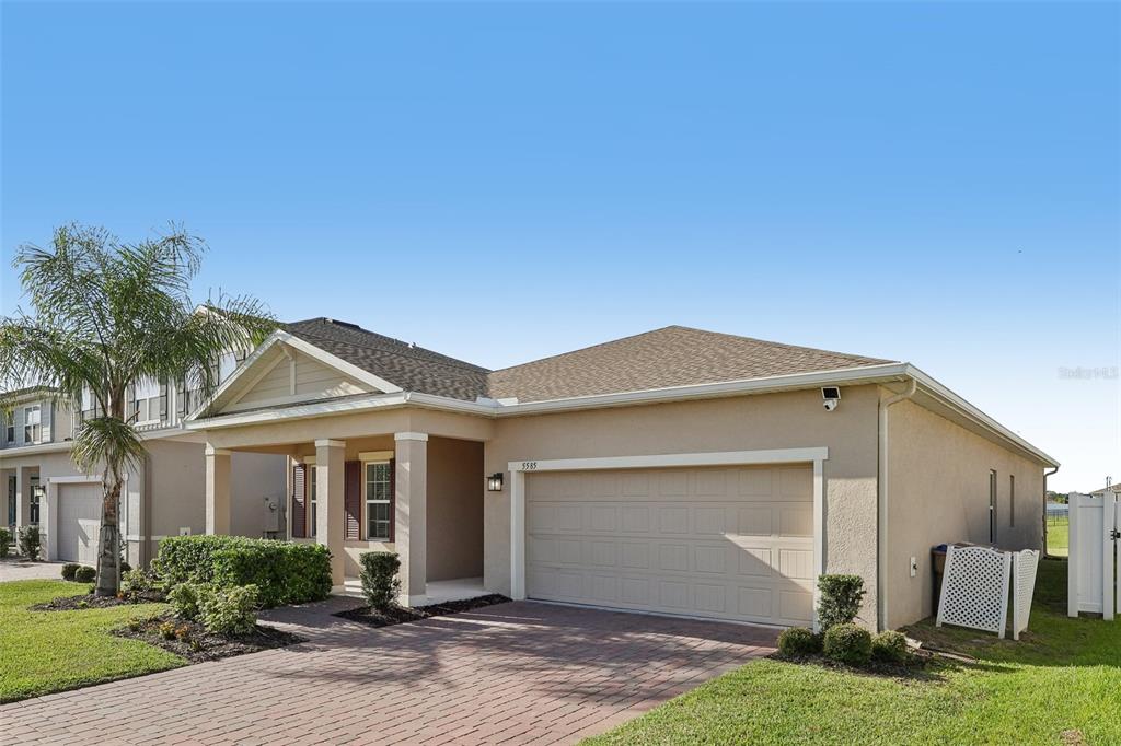 A single-story house with a beige stucco exterior, a two-car garage, and a brick driveway — 5585 VIGO LOOP, ST CLOUD, FL