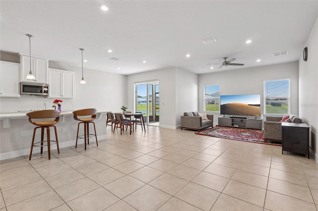 An open-concept living room and kitchen featuring tile floors, white cabinetry, and a sliding door — 5585 VIGO LOOP, ST CLOUD, FL