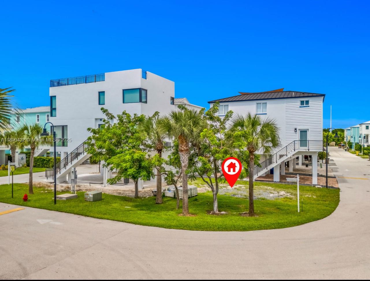 Two elevated white houses stand on a grassy lot with palm trees under a sky — 94825 Overseas Hwy, Key Largo FL 33037, KEY LARGO, FL