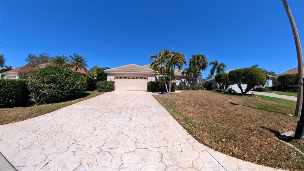 A single-story house with a beige exterior, a two-car garage, and palm trees in front — 11837 GRAND ISLES LANE, FORT MYERS, FL