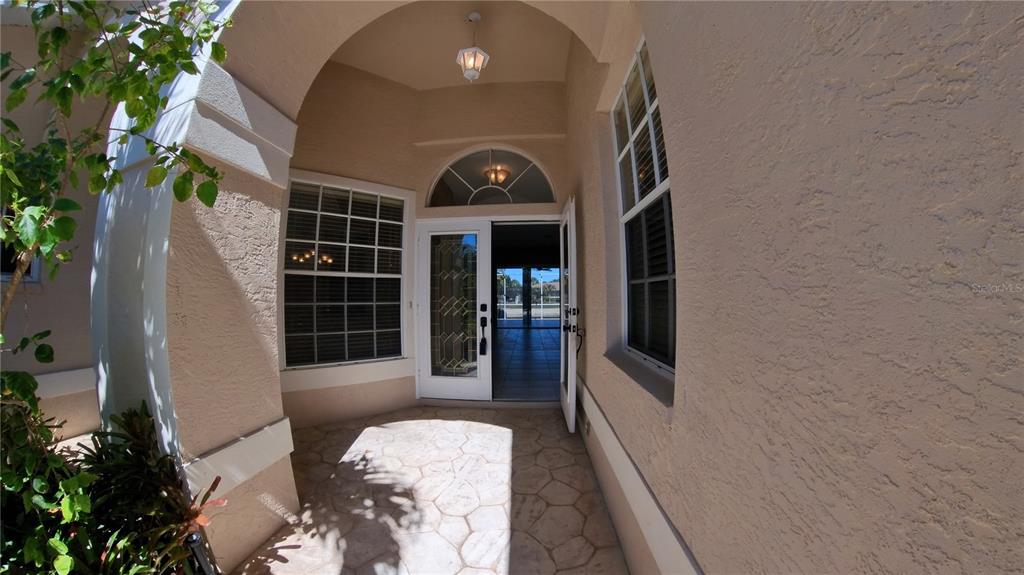 The exterior of a house features a screened-in patio and a large flowering crape myrtle — 11837 GRAND ISLES LANE, FORT MYERS, FL