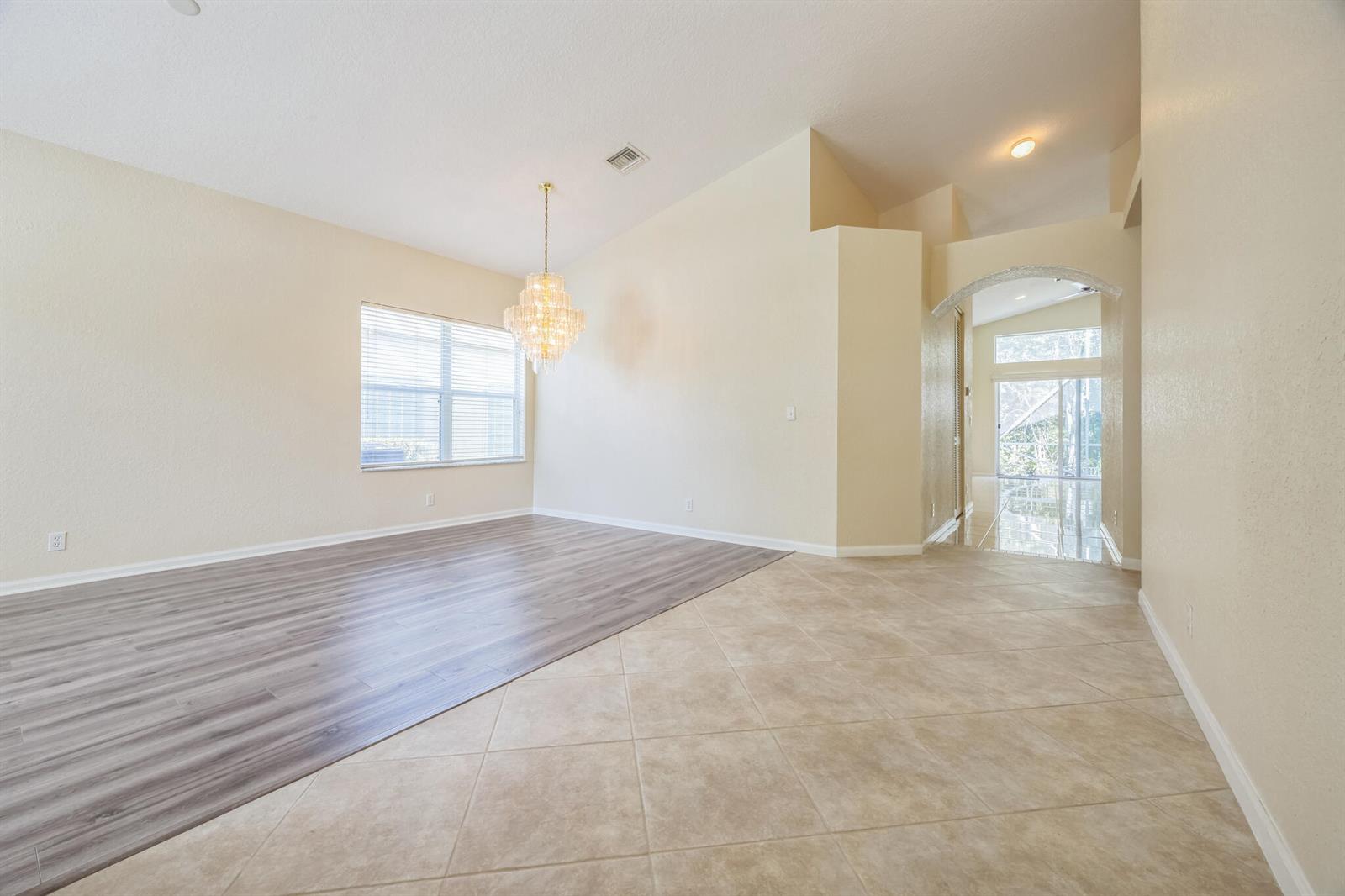 A room featuring a mix of wood-look laminate flooring and beige tile with a chandelier — 5780 Saddle Trail Lane, Lake Worth FL 33449, LAKE WORTH, FL