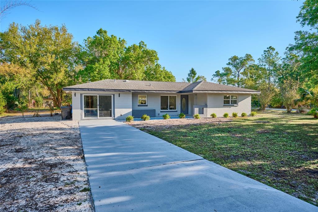 A single-story gray house with a concrete driveway and a large front yard — 3500 ORCHID DRIVE, INDIAN LAKE ESTATES, FL