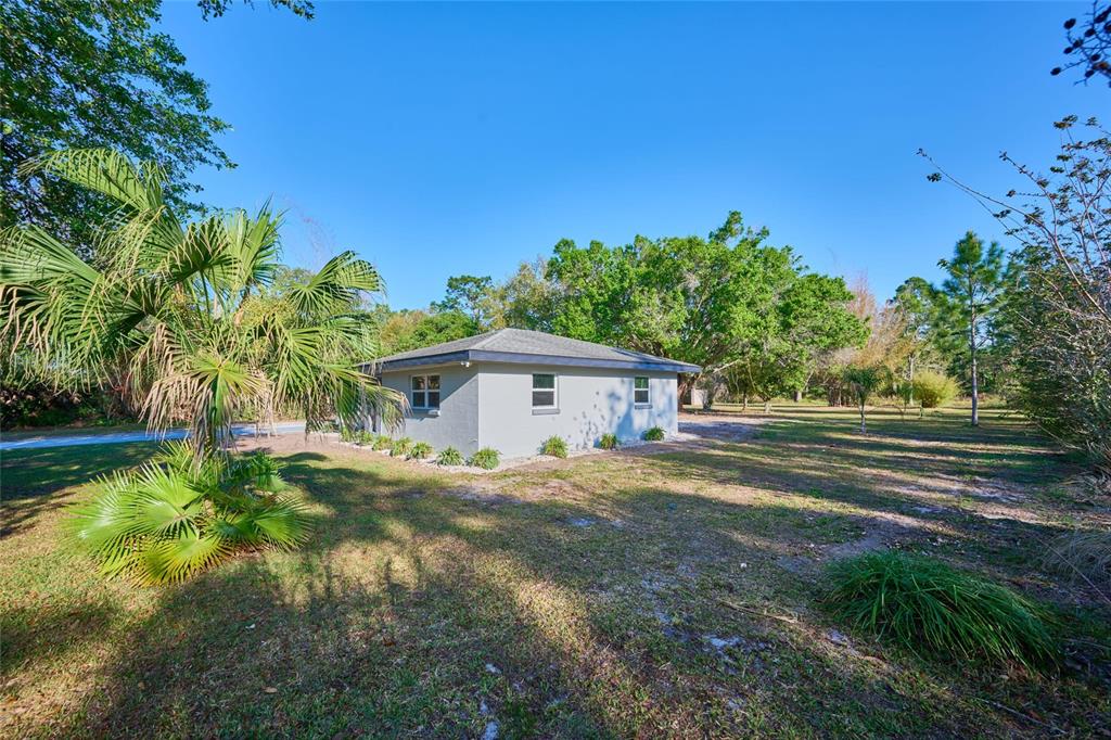 A light-colored, single-story house sits on a grassy lot surrounded by trees and palms — 3500 ORCHID DRIVE, INDIAN LAKE ESTATES, FL