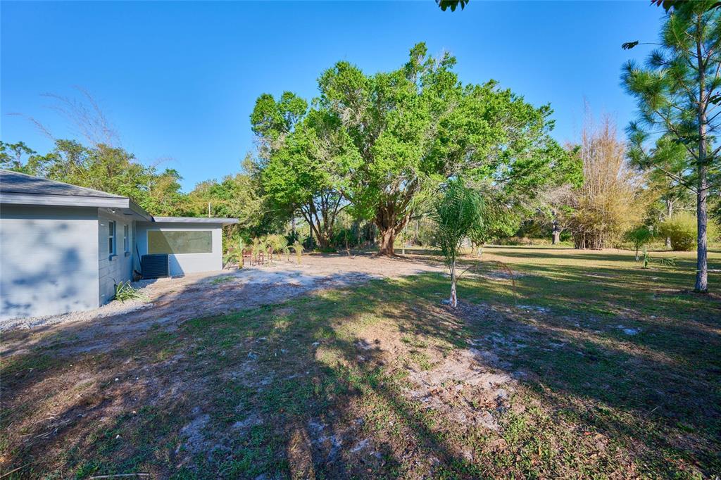 A side view of a house exterior with a large tree and a grassy yard — 3500 ORCHID DRIVE, INDIAN LAKE ESTATES, FL
