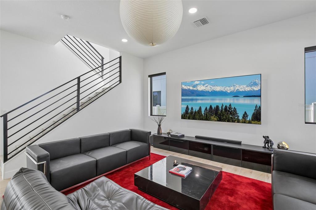 A modern living room features a black sofa, red rug, and a wall-mounted television — 7519 N COOLIDGE AVENUE, TAMPA, FL