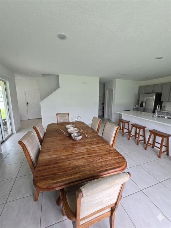 A dining area with a wooden table and chairs sits adjacent to a kitchen island — 216 CITRINE LOOP, KISSIMMEE, FL