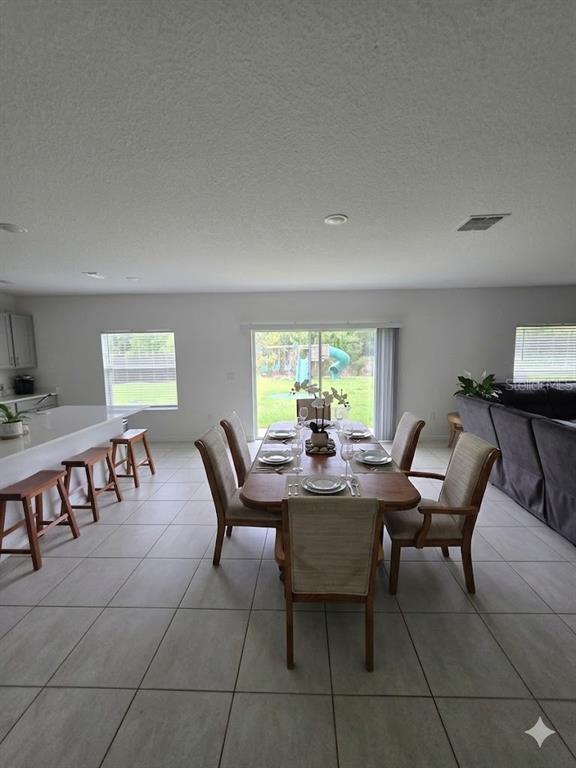 A dining area with a wooden table and chairs sits adjacent to a kitchen island — 216 CITRINE LOOP, KISSIMMEE, FL