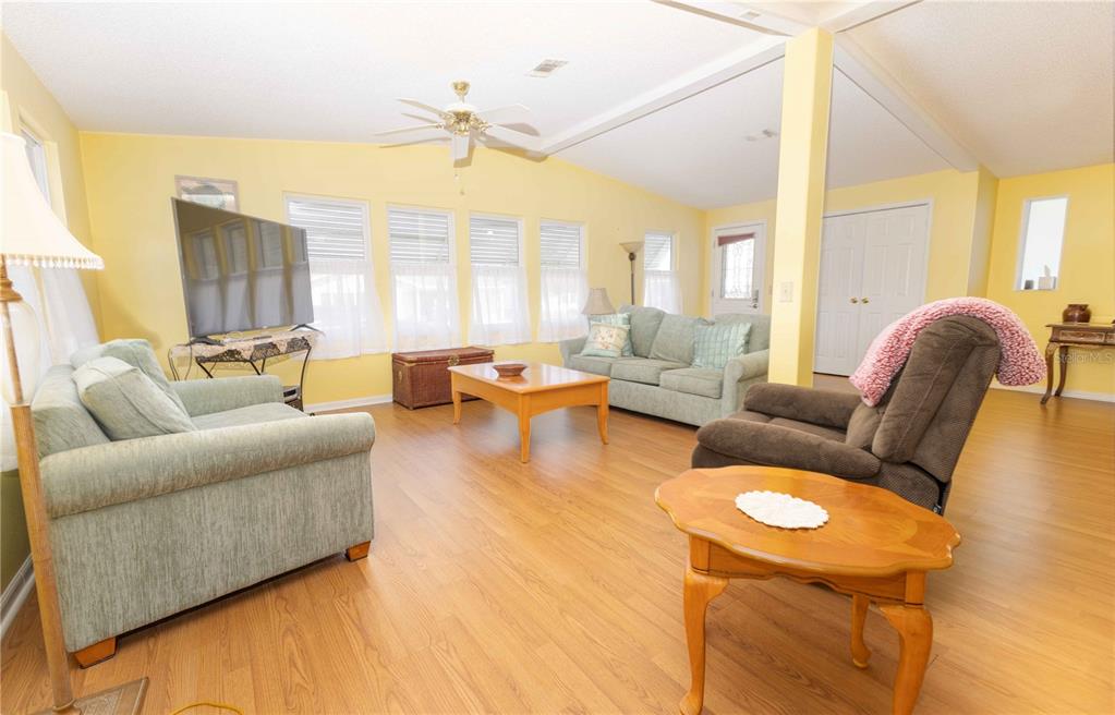 A living room with light yellow walls, wood-look flooring, two sofas, and a recliner — 1159 PARADISE DRIVE, LADY LAKE, FL