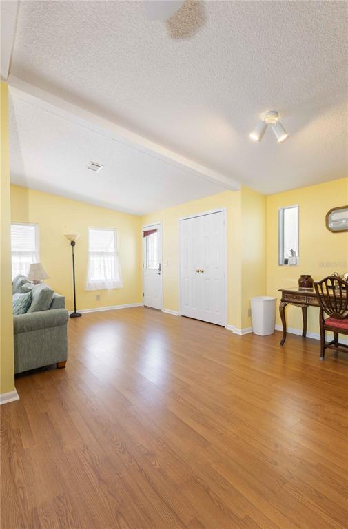 A living room with yellow walls, wood-look flooring, a sofa, and a desk — 1159 PARADISE DRIVE, LADY LAKE, FL