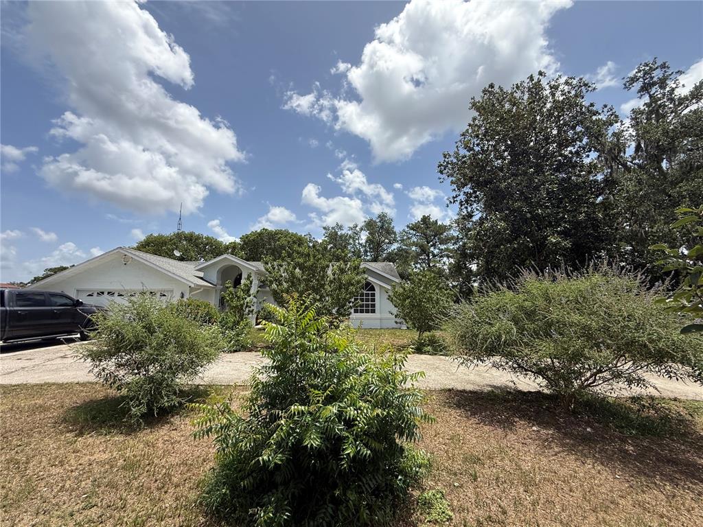 A white single-story house with a driveway and a black truck in the front yard — 2156 NEW AZORA ROAD, SPRING HILL, FL