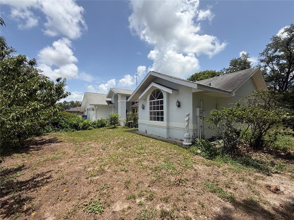 A light-colored house with a gabled roof and a grid-patterned window stands in a yard — 2156 NEW AZORA ROAD, SPRING HILL, FL