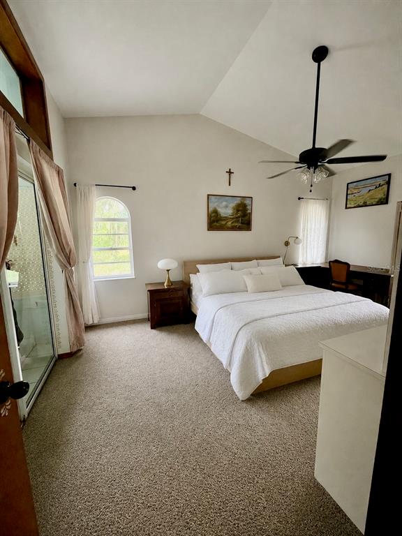 A bedroom features a vaulted ceiling, a ceiling fan, a bed, and a sliding glass door — 2156 NEW AZORA ROAD, SPRING HILL, FL
