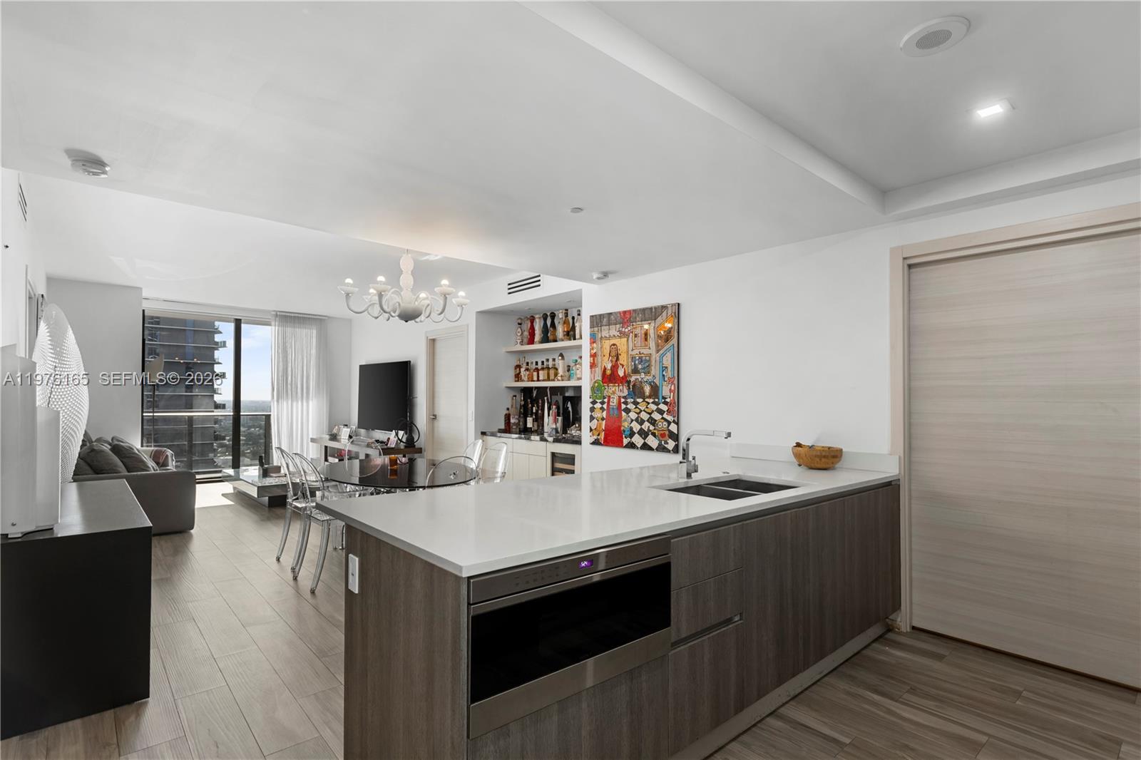 A modern kitchen island with a built-in microwave faces an open-concept living and dining area — 801 S Miami Ave # 3310, Miami FL 33130, MIAMI, FL