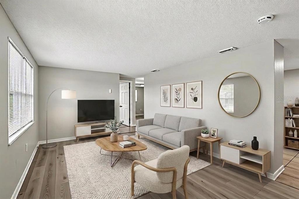 A living room features light gray walls, wood-look flooring, a sofa, and a television — 4922 PANORAMA AVENUE, HOLIDAY, FL