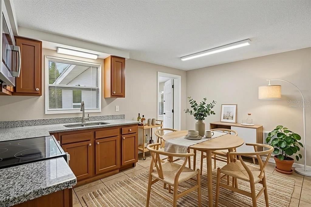 A kitchen and dining area with wood cabinets, granite countertops, and a round wooden table — 4922 PANORAMA AVENUE, HOLIDAY, FL