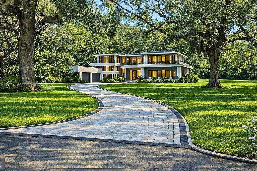 A modern two-story house with a paved driveway sits on a large, tree-filled lawn — 9979 Fairchild Way, Coral Gables FL 33156, CORAL GABLES, FL