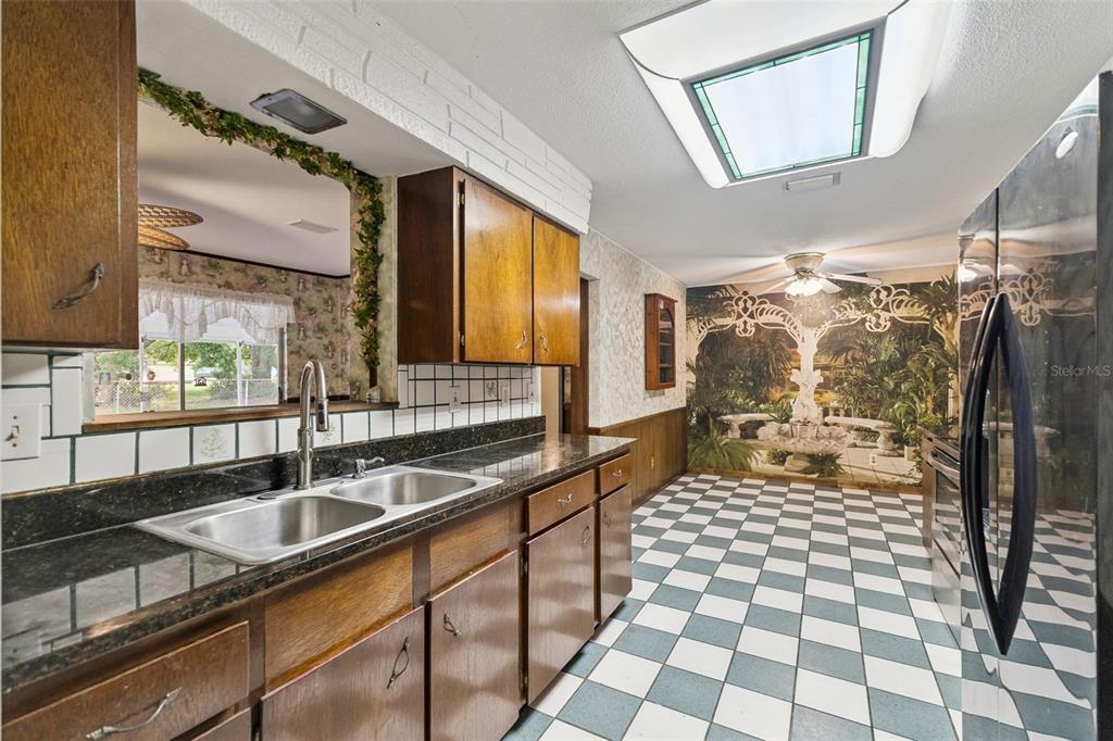 A kitchen features wood cabinets, dark countertops, a checkerboard floor, and a large wall mural — 1507 MARGINA AVENUE, DAYTONA BEACH, FL