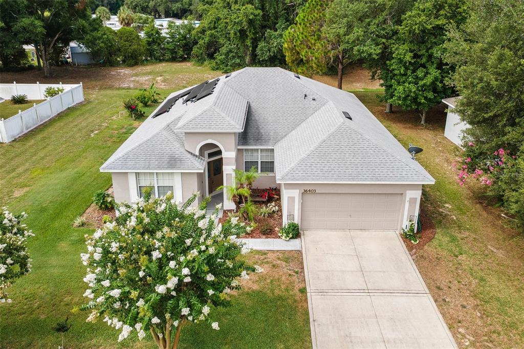 An aerial view of a single-story suburban house with a gray roof and concrete driveway — 36403 GRAND ISLAND OAKS CIRCLE, GRAND ISLAND, FL