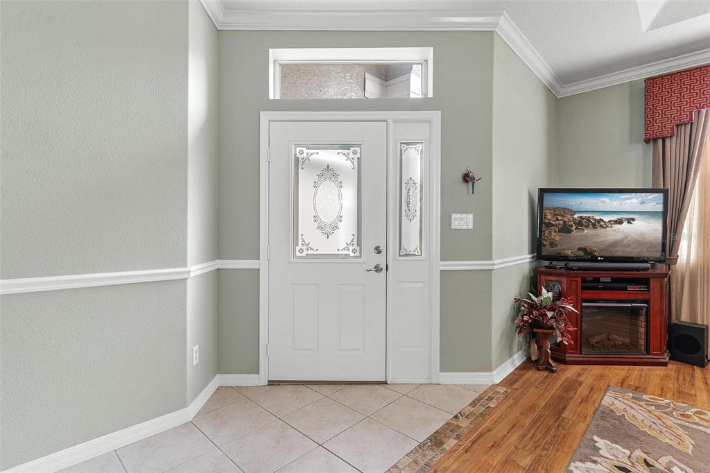 An entryway features a white front door with glass inserts, tile flooring, and light walls — 36403 GRAND ISLAND OAKS CIRCLE, GRAND ISLAND, FL