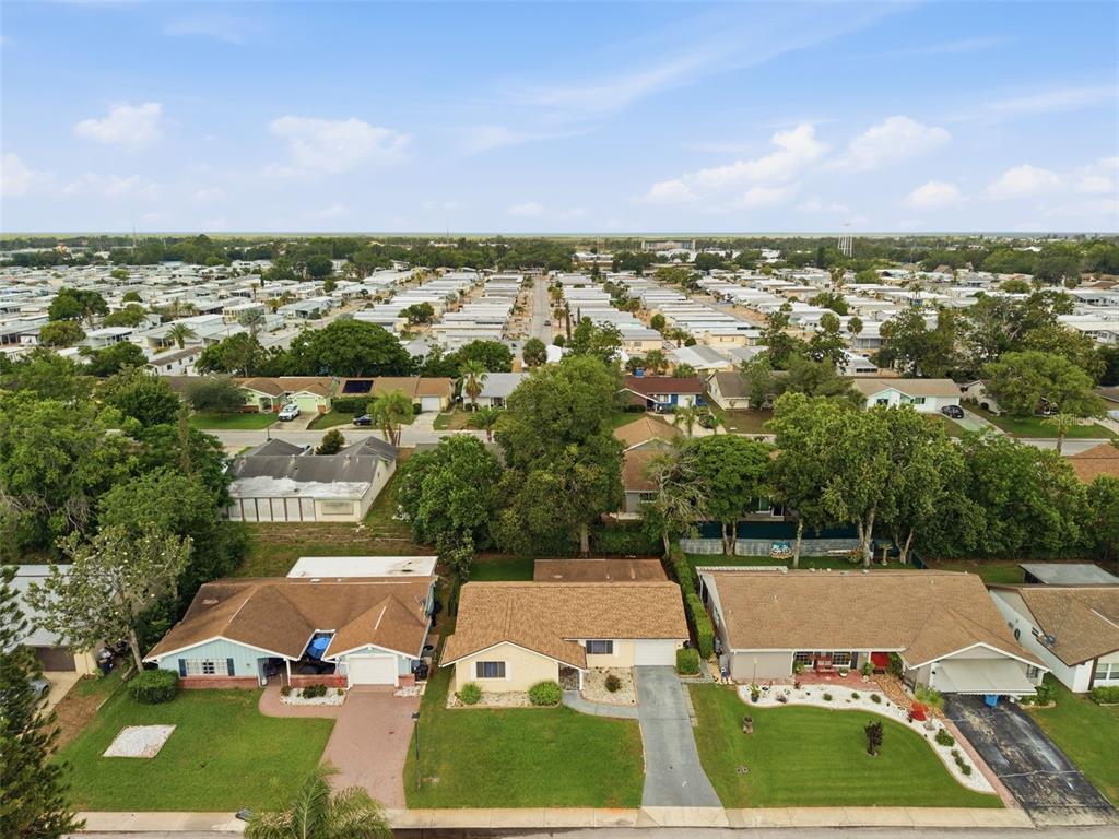 An aerial view shows three suburban houses with lawns and driveways in a residential neighborhood — 12219 QUAIL RUN ROW, BAYONET POINT, FL
